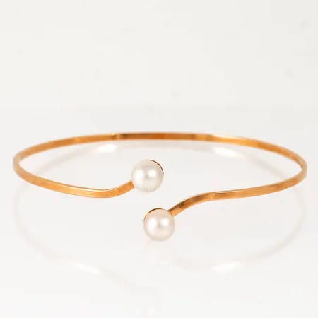 Stelt armband i 18K guld med två odlade saltvattenspärlor Ø 6,4mm. Det är 1,8 mm brett, har ett innermått på c:a 18 cm och väger 5,8g. Tillverkat 1958 av Svedboms Guldsmeds AB i Vetlanda.