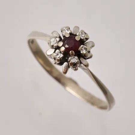 Ring i 18K vitguld, stl 19½, bredd 2,1-8,5mm, 1st röd sten, mått Ø3mm, 6st små vita stenar, vikt 2,98g.