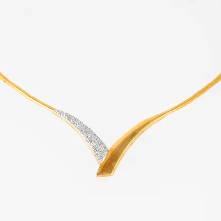Halvstelt, v-format collier i 18K guld med glitterdekor. Det är c:a 42 cm långt (plus "tårtbiten" nere i v:et), 2,1 mm brett och väger 13,0g. Mittpartiet hänger ner c:a 30 mm. Kistlås. Stämplat GHA 750. Fint skick! Originaletui från Hallbergs guld medföljer. 