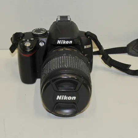 Digital systemkamera, Nikon D3000, serie-nr 6323420, sprucken display, objektiv Nikon DX 18-105mm, serie-nr 32847024, levereras med väska samt laddare. Skickas med postpaket.