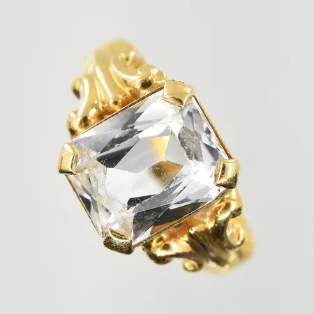 Ring med vit sten, stl 16½, bredd 3-10 mm, gravyr, skev och bucklig skena, 18K+23K. Vikt: 4,4 g