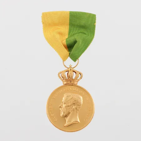 Medalj Gustaf V, gravyr, 23/18k, totalvikt med tygband 31.1 gram. Vikt: 31,1 g