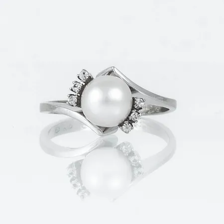 Ring i vitt guld 18K med en 7,3 mm´s odlad saltvattenspärla och diamanter 6 x c:a 0,01ct. Den är 2 - 9,7 mm bred, är i storlek 17 och väger 3,5g. Gravyr.