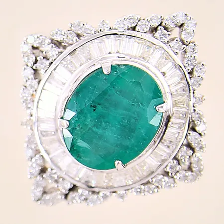 Ring med smaragd, mått: ca 15x12mm, samt briljantslipade diamanter ca 60 x 0,01ct och baguetteslipade diamanter ca 48 x 0,02-0,03ct, stl: 18¼, bredd: 4,1-33mm, oljebehandlad smaragd med nagg på fasetter, diamanter med flertalet nagg, omrodierad, vitguld, ostämplad 18K  Vikt: 15,7 g