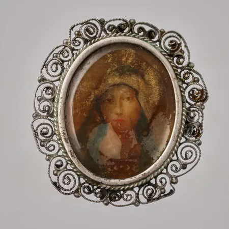 Brosch i silver med madonna-bild , mått 29,8x32,6mm, 800/1000, missfärgad plast, vikt 6,88g.