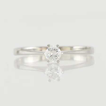 Ring vitguld med solitär diamant på ca 0.23 ct, storlek 19 mm, bredd 1.8-4.2 mm, 18k. Vikt: 1,6 g