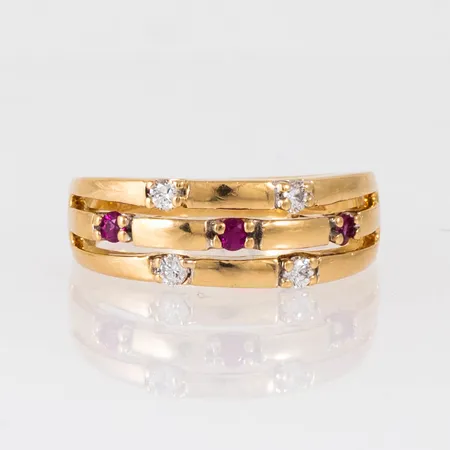 Ring i 18K guld med 4 x ca 0,03ct briljantslipade diamanter, 3 rubiner Ø 2 mm. Den är i storlek 17, är 2,7 - 7,2 mm bred och väger 7,0g. Stämplad GHA, 750. 