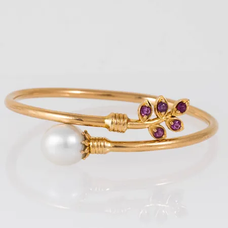 Armring i 18K guld med en odlad sötvattenspärla Ø 11,2 mm och fem rosa stenar Ø 2,5 mm fattade i lövdekor. Innermått 16 cm, bredd 2,9 - 14,5 mm. Vikt: 12,6g. Spricka. Ostämplad.