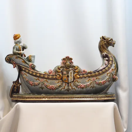 Jardinjär Rörstrand i majolika i form av båt med roddare och galjonsfigur, Polykrom glasyr och rik dekor i relief. Djupstämplad och målad stämpel "Rörstrand" 1800-talets slut/tidigt 1900-tal, Längd 45 höjd 27 cm, limmat huvud, näsa, åra samt hand med små skador, krackelyr, glasyrspricko, ytslitage.  Vikt: 0 g Skickas med postpaket.