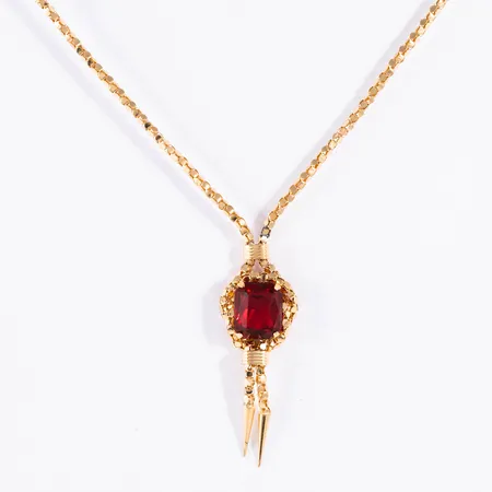 Collier i 18K guld med röd sten i integrerat hänge. Kedjan är ca 50 cm lång, 2,2 mm bred, hängets längd ca 4,5 cm. Vikt: 12,5g. Springring. Dålig lagning av kedjan ovanför hänget.