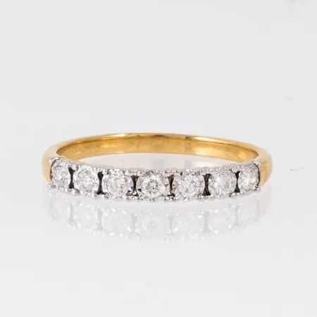 Ring i 18K guld med 7 x ca 0,04ct briljantslipade diamanter. Den är i storlek 18¼, är 1,9 - 3 mm bred och väger 2,4g. Stämplad GHA, 750. Fattning med rhodiumyta. 