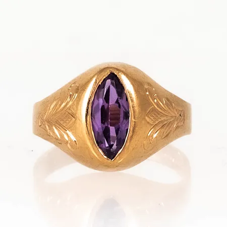 Ring i 18K guld med mönstergravyr och navettslipad lila sten. Den är i storlek 19, är 3 - 13,5 mm bred och väger 4,1g. Stämplad N9 (1963), SWL (Sigvard Ljungström, Stockholm). Sten något lös. Gravyr.