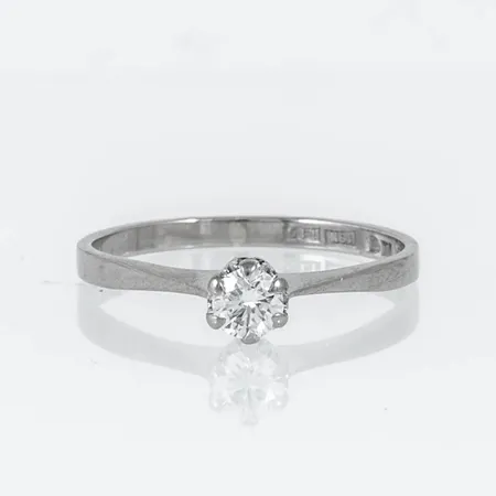 Ring i 18K vitguld med 1 x 0,23ct briljantslipad diamant. Den är i storlek 17½, är 1,7 - 4,5 mm bred och väger 2,0g. Stenstorlek 0,23ct ingraverad. Stämplad I10 (1983), GIA (Guldsmeders Inköps AB, Uppsala)