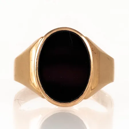 Klackring i 18K guld med svart sten (onyx el. agat). Den är i storlek 20¾, är 3 - 16,5 mm bred och väger 5,4g. Gravyr. 