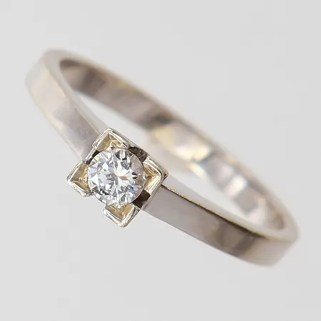 Ring med briljantslipad diamant 1 x 0,12ct enligt gravyr, stl: 16¾, bredd 2-4mm, vitguld 18K.  Vikt: 3,2 g