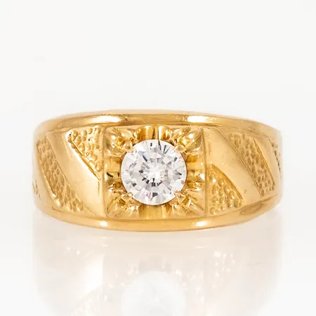 Doserad ring i 18K guld med vit sten och strukturmönster. Den är i storlek 21½, är 4 - 11 mm bred och väger 7,5g. 