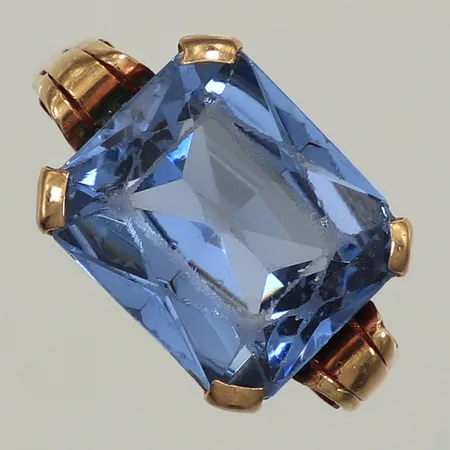 Ring, blå sten troligen syntetisk spinell, stl 18, bredd 12mm, slitna fasetter,18K Vikt: 6,4 g