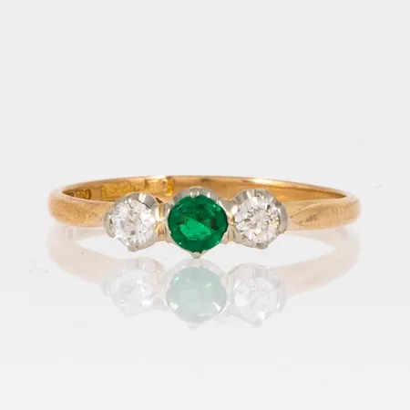 Ring i 18K guld med grön sten och 2 x c:a 0,07ct gammalslipade diamanter, kulettfacett. Den är i storlek 16½, är 1,5 - 4 mm bred och väger 1,7g. Grön sten med naggade fasetter och skadad rondist.