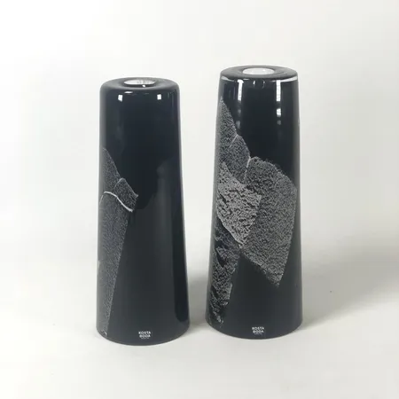 Ett par ljusstakar/vaser, Anna Ehrner, Kosta Boda, underfång i lila med vit och grå dekor, signerade Kosta Boda A Ehrner 7060801, även etikettmärkta, höjd 19 och 20cm Skickas med postpaket.