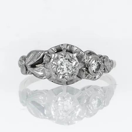 Ring i 18K röd- och vitguld: 1 x antikslipad diamant c:a 3,5 - 3 mm och 1 x c:a 0,10ct briljantslipad diamant. Den är i storlek 16½, är 1,4 - 8 mm bred och väger 2,8g. 