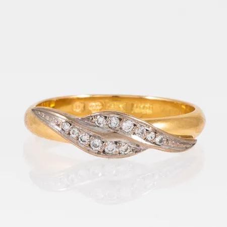 Ring i 18K röd- och vitguld. Dekor i vitguld med 4 x c:a 0,005ct och 8 x c:a 0,01ct briljantslipade diamanter. Den är i storlek 17¾, är 2,7 - 5 mm bred och väger 3,5g. Stenstorlek 0,10ct W/vs ingraverad. Stämplad 18K & kattfot.