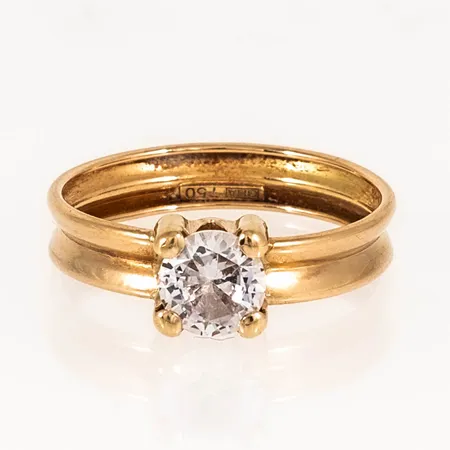 Ring i 18K guld med vit sten Ø 6 mm. Den är i storlek 17¾, är 4 - 6,5 mm bred och väger 1,3g. Stämplad GHA, 750. Lös sten. 