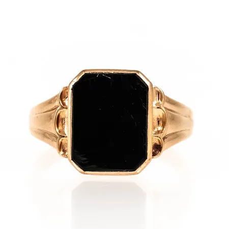 Klackring i 18K guld med svart sten (agat el. onyx). Den är i storlek 21¼, är 2,7 - 14,5 mm bred och väger 4,8g. Repig sten.