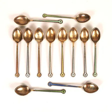 Tolv moccaskedar med emaljdekor, CG Hallberg, Stockholm, 1940, längd 9,5cm, mindre emaljbortfall, någon med gravyr, i etui, silver.  Vikt: 119,4 g