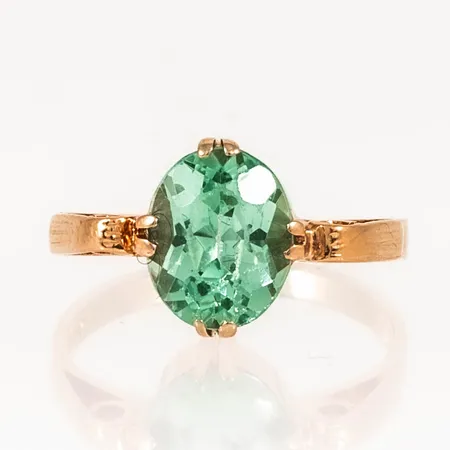 Ring i 18K guld med mintgrön sten. Den är i storlek 16¾, är 2 - 10 mm bred och väger 2,9g. Naggade fasetter.