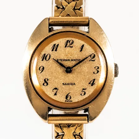Damur, Eterna Matic Sahida, guld på stål med band i 18K guld. Boett Ø 25 mm, automatiskt urverk. Länkens längd 18 - 18,5 cm, 7 - 8 mm bred, viklås. Bruttovikt: 33,5g. Repigt plexiglas. Länk c:a 15g.
