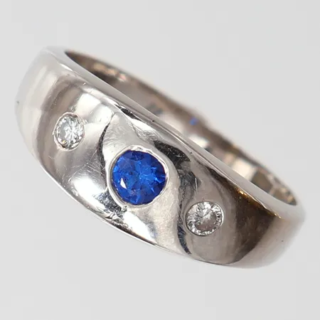 Lordring med safir 1 x ca 0,15ct samt diamanter 2 x ca 0,04ct, stl: 18, bredd 3,5-7,5mm, Hedens Guldsmeds Ab Bröderna, Ängelholm 1982, sprickor i skena, vitguld 18K.  Vikt: 6,1 g