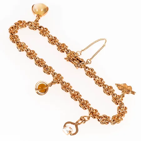 Armband i 18K guld med 4 berlocker: bl.a. en sockertång. Det är 18,7 cm långt, 2,8 - 5,5 mm brett och väger 16,0g. Kistlås, säkerhetskedja. Stämplad B9 (1952), KHM (Guldsmed H.Michelsson Eftr AB, Stockholm), 18K & kattfot. Vass del på en länk, datumgravyr på berlock.