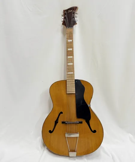 Umeåtillverkad orkestergitarr Frii; enligt uppgift från 1947. Skavanker, lagningar i fäste, lackkrackeleringar, rejäla sprickor i kantlisten.  Skickas med Bussgods eller PostNord