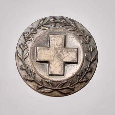 Sjuksköterskebrosch i silver, mått Ø 31,3mm, 830/1000, tillverkad av Sporrong, år 1972, vikt 13,87g.