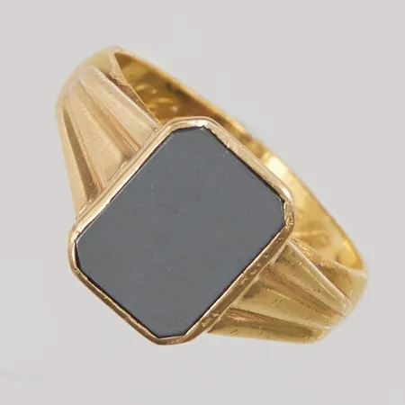 Klackring, hematit, Ø19¾, bredd: 4,9-13,6mm, gravyr, skev skena, repig sten, skena i 23K, fattning i 18K, 10,8g.