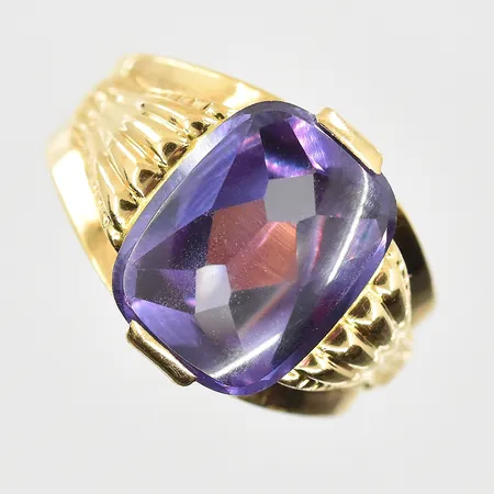 Ring med lila sten, stl 17¼, bredd 3-13 mm, sten sitter något löst i fattning, 18K. Vikt: 4,5 g