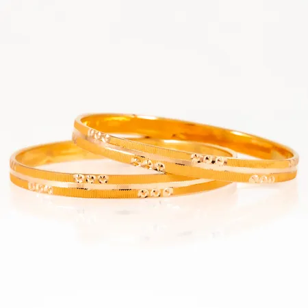 Två armringar i 21K guld med mönsterdekor. De är 6 mm breda, har en innerdiameter på 57,5 mm och väger 16,0g. Ihåliga.