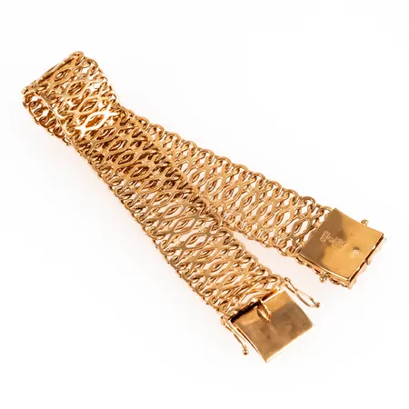 Armband i 18K guld. Det är 19,5 cm långt, 17,5 mm brett och väger 39,1g. Kistlås. Stämplad E10 (1979), BRS (Sahlgrens Guldsmide, Västerhaninge), 18K & kattfot.