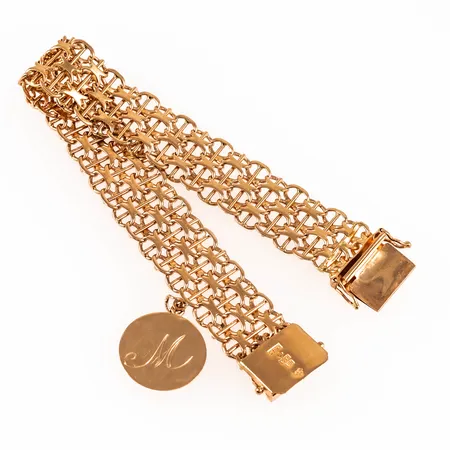 Armband, X-länk med stav i 18K guld. Det är 18,5 cm långt, 15,5 mm brett och väger 28,3g. Kistlås. Pålödd rondell med gravyr. Stellödning närmast låset.