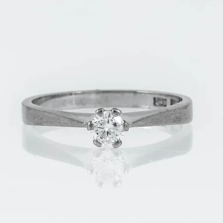 Ring i 18K vitguld med 1 x 0,15ct briljantslipad diamant. Den är i storlek 15¾, är 1,9 - 4 mm bred och väger 2,3g. Stämplad ÄGS (Älvängens Guld & Silver, Göteborg), O10 (1988), 18K & kattfot.