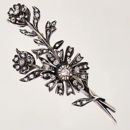 Brosch, i form av blomsterkvist, med dekor av rosenslipade diamanter, nål samt del av undersidan i 18K, dekor samt fattningar i silver, mått 65x26mm, svensk importstämpel, mittendel troligen defekt, hålls ihop med hjälp av tråd, silver 830/1000 Vikt: 14 g