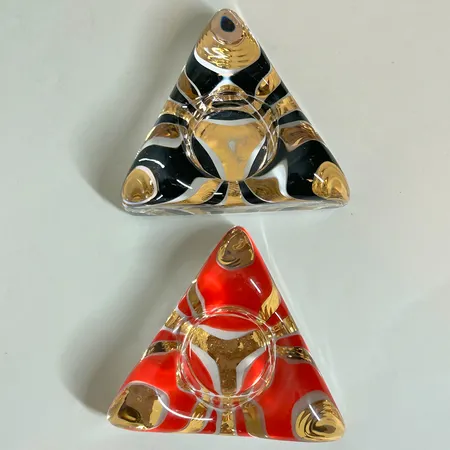 2 Ljushållare Kosta Boda, Piece of cake av Ulrica Hydman-Vallien, svart & guld, röd & guld, handmålade & signerade, bruksslitage