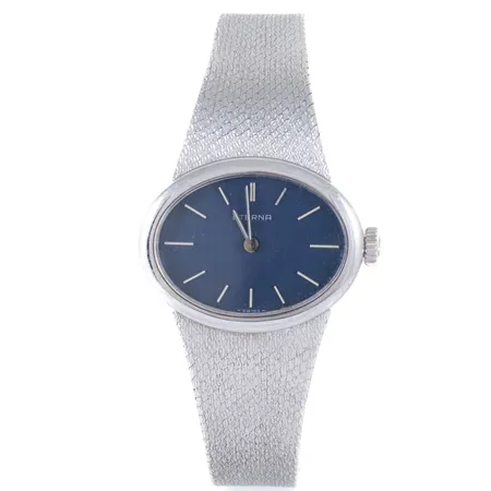 Damur Eterna i 18K vitguld med integrerat band i 18K. Ställbar längd 15,5/16 cm. Boett 27,5 x 21,5 mm, blå urtavla, safirglas, quartz, defekt krona (går ej att ställa). Går ej, batteribyte krävs? Bruttovikt: 53,8g.