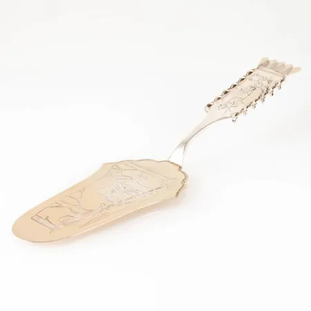 Tårtspade i silver med handgraverat samemotiv. Delvis förgylld (nött). Den är 215 mm lång och väger 53,8g. Från CO Persson i Haparanda. Bruksskick.