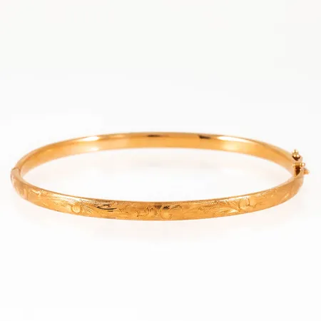 Stelt armband i 18K guld med graverad dekor på halva. Det är 4 mm brett, har ett innermått på 18,5 cm och väger 8,3g. Istickslås & säkerhetsåtta. Stämplat 18K. Personlig gravyr på insidan.