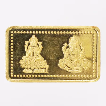 Guldtacka med dekor av hinduisk gud avbild, längd 41mm, bredd 24mm, PC jeweller Ltd, 24K Vikt: 20 g