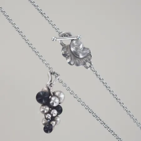Hänge med kedja, "Moonlight Grapes", Georg Jensen, Danmark, efter 1945 Kedjans längd 92 cm. Lås i form av blad. Hänge i form av druvklase, silver 925/1000. Druvklasarna i sterlingsilver fanns med i den ursprungliga Georg Jensen-modellen från 1920-talet.   Vikt: 16,6 g