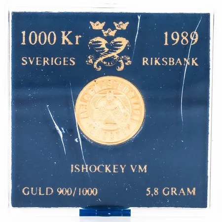 Minnesmynt "ISHOCKEY VM 1989". Ø 20 mm. Nominellt värde 1000kr. 5,8g 21,6K. Plastetui med repor / sprickor.