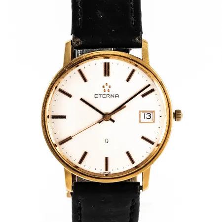Herrur Eterna i 18K guld. Boett Ø 33,5 mm, datum, quartz, gravyr "För nit och redlighet...", repigt glas, defekt läderband. Går ej, batteribyte krävs? Bruttovikt: 27,8g.
