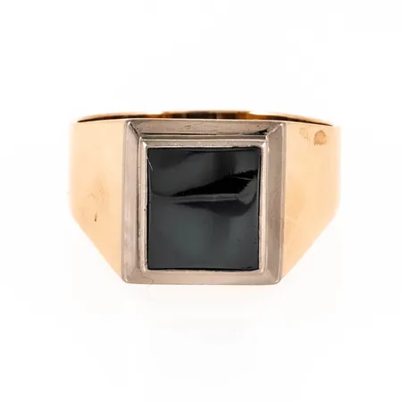 Klackring i 18K guld med en hematit; fattad i vitt guld. Den är 4,4 - 13,5 mm bred, är i storlek 21 och väger 10,6g. Tillverkad 1966 av Ceson i Göteborg.